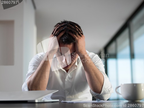 Image of frustrated young business man working on laptop computer at home