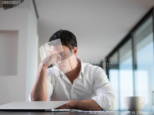 Image of frustrated young business man working on laptop computer at home