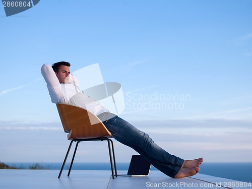 Image of relaxed young man at home on balcony