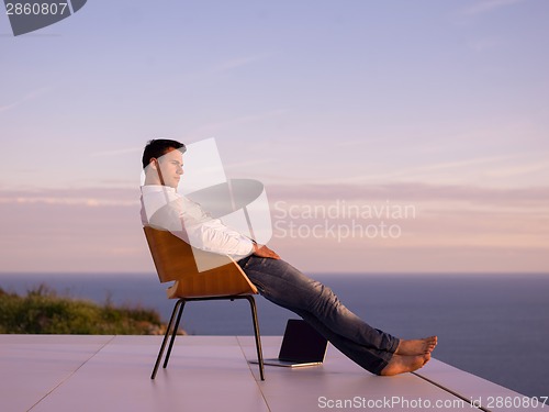 Image of relaxed young man at home on balcony