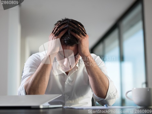 Image of frustrated young business man working on laptop computer at home