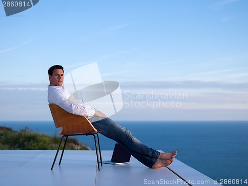 Image of relaxed young man at home on balcony