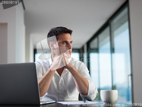 Image of business man working on laptop computer at home