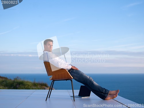 Image of relaxed young man at home on balcony