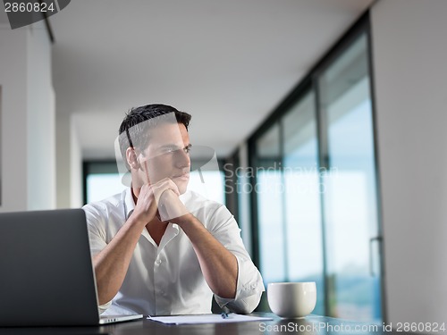 Image of business man working on laptop computer at home