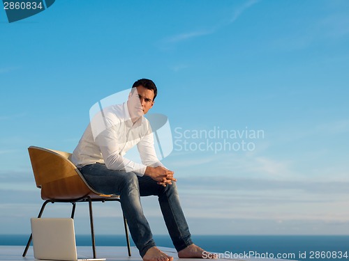 Image of relaxed young man at home on balcony