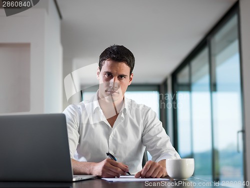 Image of business man working on laptop computer at home
