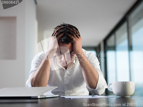 Image of frustrated young business man working on laptop computer at home