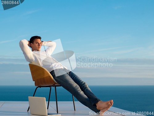 Image of relaxed young man at home on balcony