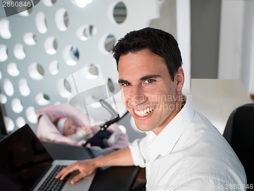 Image of man working from home and take care of baby