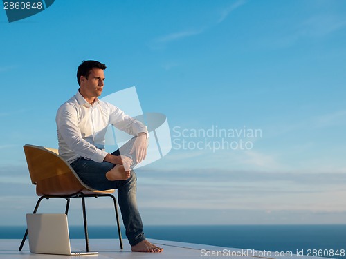 Image of relaxed young man at home on balcony