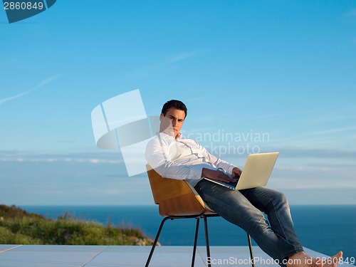 Image of relaxed young man at home on balcony