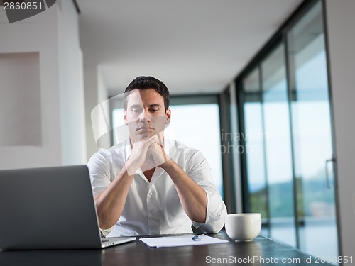 Image of business man working on laptop computer at home