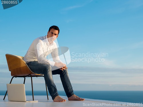 Image of relaxed young man at home on balcony