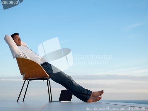 Image of relaxed young man at home on balcony