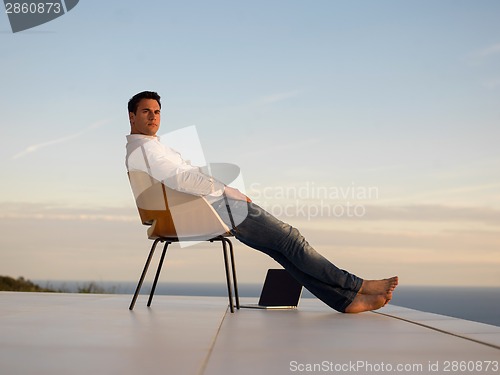 Image of relaxed young man at home on balcony