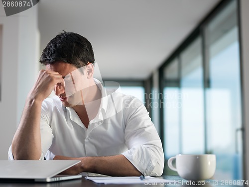 Image of frustrated young business man working on laptop computer at home