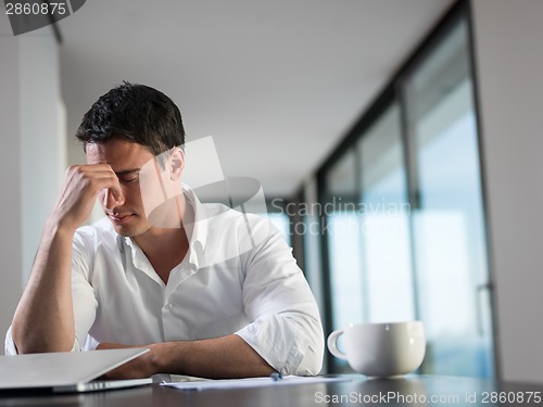 Image of frustrated young business man working on laptop computer at home