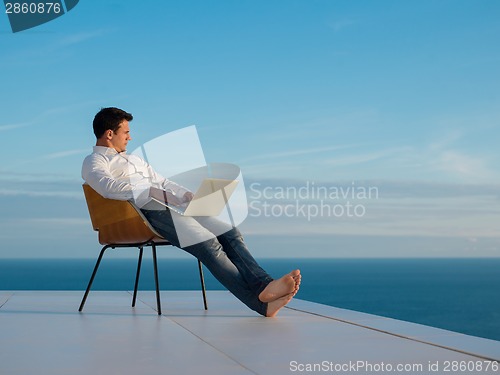 Image of relaxed young man at home on balcony