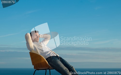 Image of relaxed young man at home on balcony