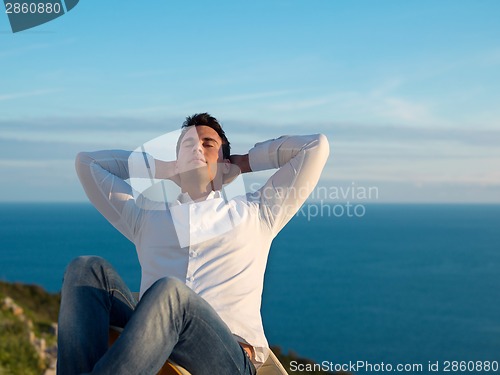 Image of relaxed young man at home on balcony