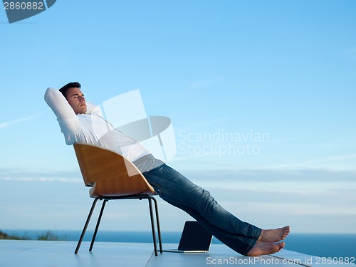 Image of relaxed young man at home on balcony