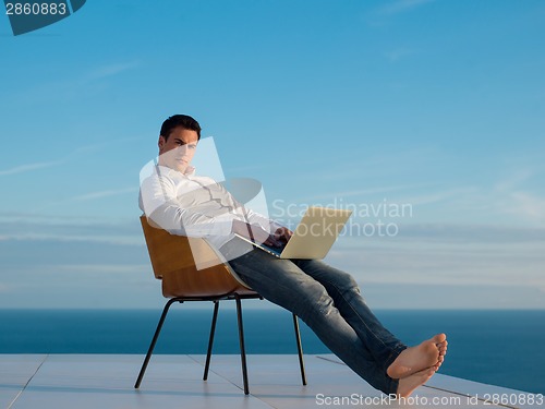 Image of relaxed young man at home on balcony