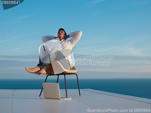 Image of relaxed young man at home on balcony