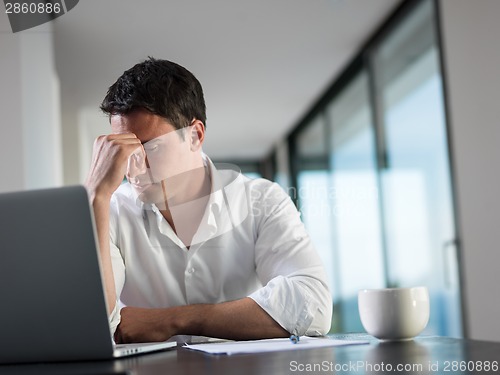 Image of frustrated young business man working on laptop computer at home