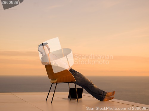 Image of relaxed young man at home on balcony