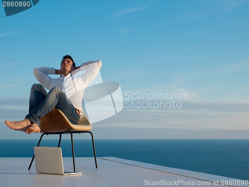 Image of relaxed young man at home on balcony