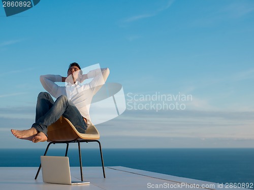 Image of relaxed young man at home on balcony