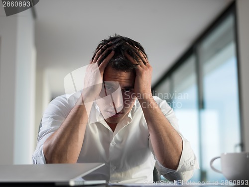 Image of frustrated young business man working on laptop computer at home