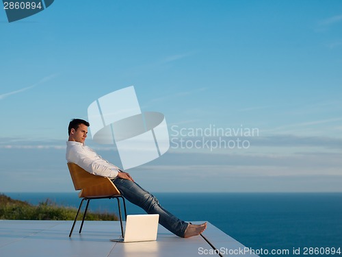 Image of relaxed young man at home on balcony