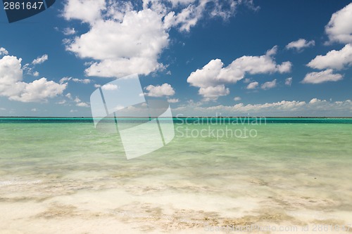 Image of blue sea or ocean, white sand and sky with clouds