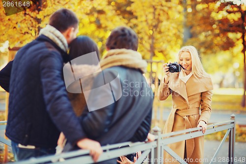 Image of group of friends with photo camera in autumn park