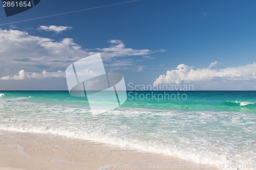 Image of blue sea or ocean, white sand and sky with clouds