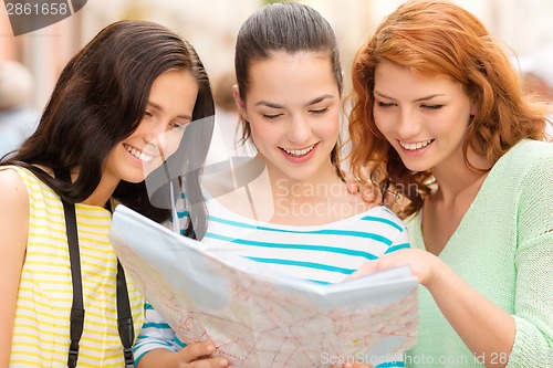 Image of smiling teenage girls with map and camera