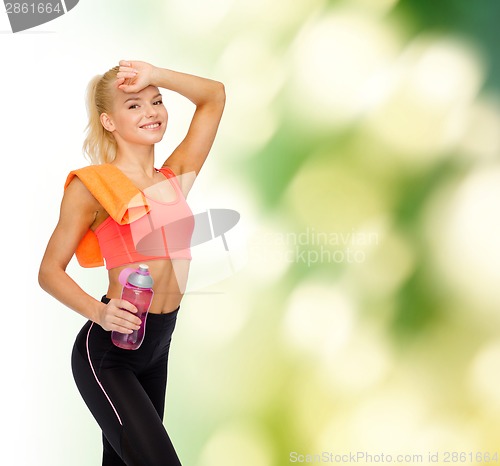 Image of smiling sporty woman with towel and water bottle