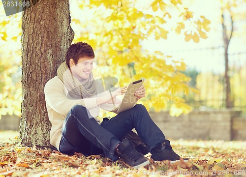 Image of man with tablet pc in autumn park