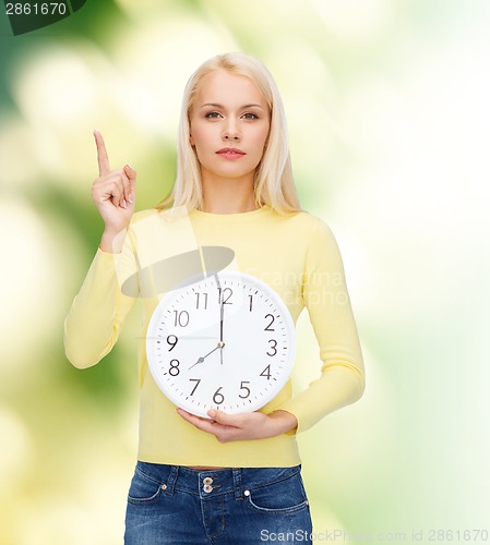 Image of student with wall clock and finger up