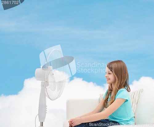 Image of smiling little girl with big fan at home