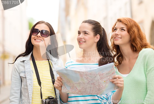 Image of smiling teenage girls with map and camera