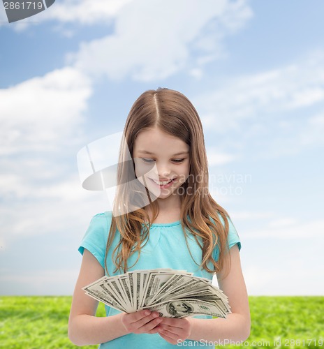 Image of smiling little girl looking at dollar cash money