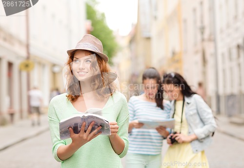 Image of smiling teenage girls with city guides and camera