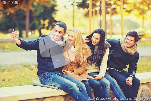 Image of group of friends taking selfie in autumn park