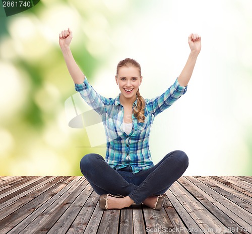 Image of young woman in casual clothes sitting on floor