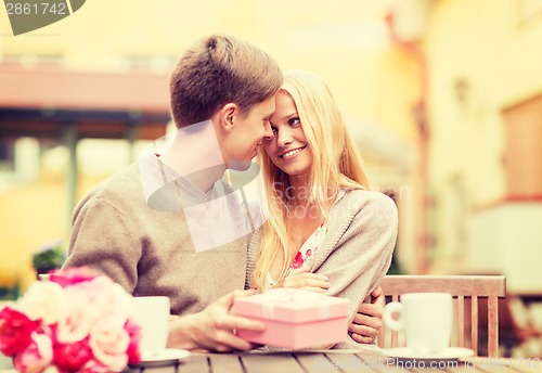 Image of romantic happy couple with gift in the cafe