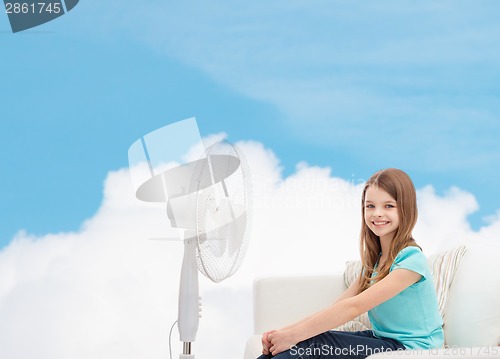 Image of smiling little girl with big fan at home