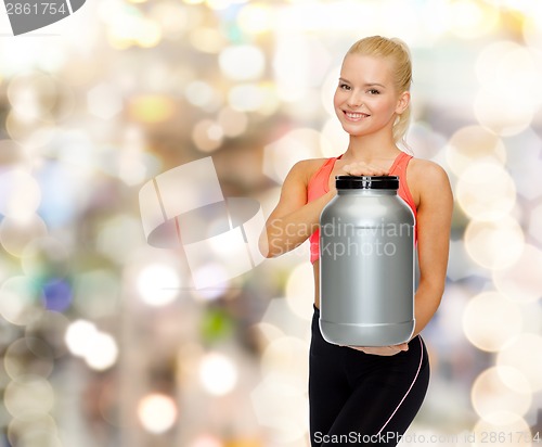 Image of smiling sporty woman with jar of protein